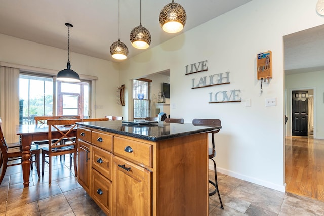 kitchen with dark stone countertops, a kitchen island, pendant lighting, and a kitchen breakfast bar