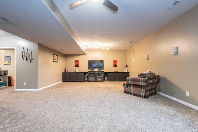 carpeted living room featuring ceiling fan and a textured ceiling