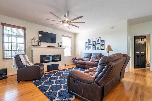 living room featuring a textured ceiling, ceiling fan, and light hardwood / wood-style flooring