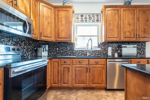 kitchen with backsplash, appliances with stainless steel finishes, sink, and dark stone countertops