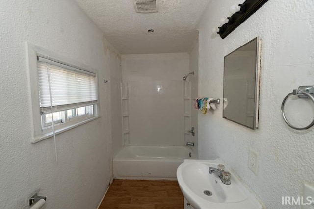 bathroom with tub / shower combination, a textured ceiling, sink, and hardwood / wood-style floors