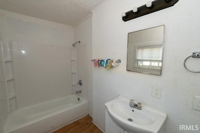 bathroom featuring a textured ceiling, shower / bathing tub combination, vanity, and hardwood / wood-style flooring