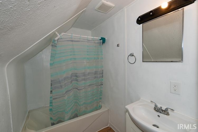 bathroom with shower / bathtub combination with curtain, a textured ceiling, and vanity