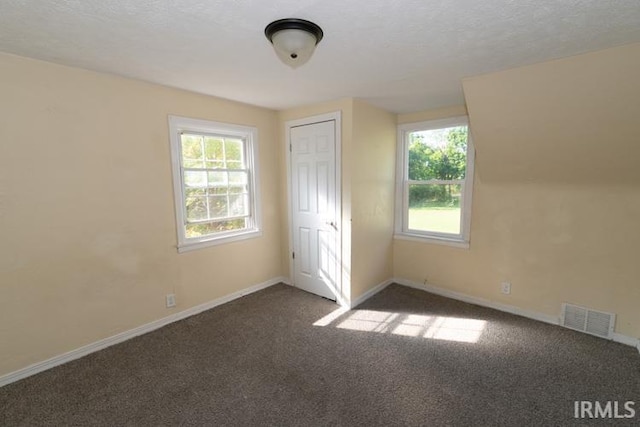 unfurnished bedroom featuring a closet, multiple windows, a textured ceiling, and carpet