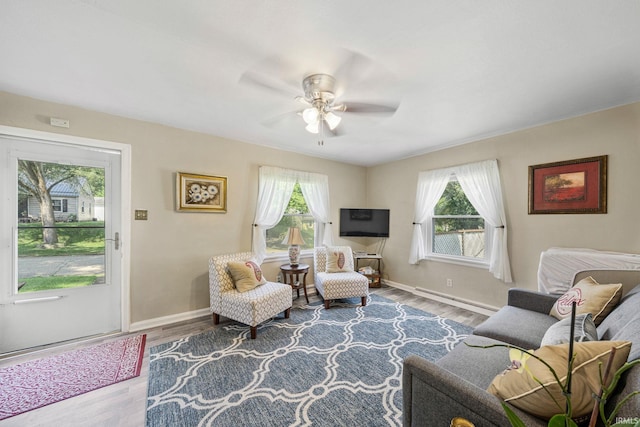 living room featuring hardwood / wood-style floors, baseboard heating, and ceiling fan