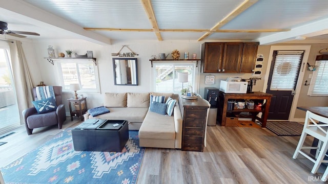 living area with ceiling fan, light wood finished floors, and beam ceiling