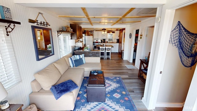 living room featuring beamed ceiling, wood finished floors, and baseboards