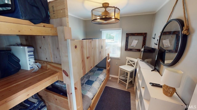 bedroom with baseboards, crown molding, and wood finished floors