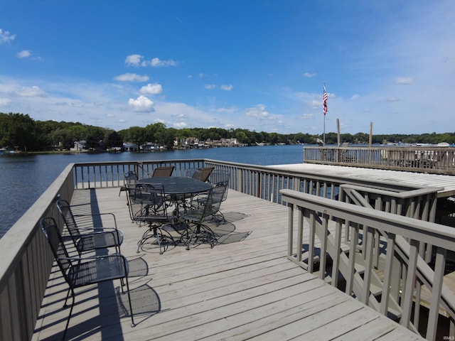 view of dock with outdoor dining space and a water view