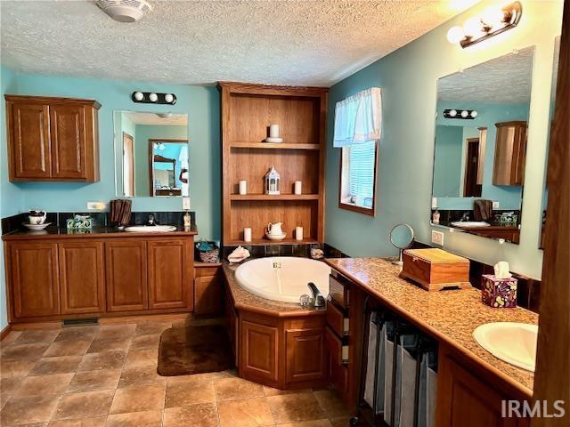 bathroom with vanity, a textured ceiling, and a bathing tub