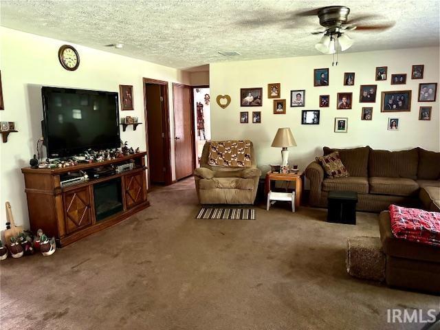 carpeted living room featuring a textured ceiling and ceiling fan