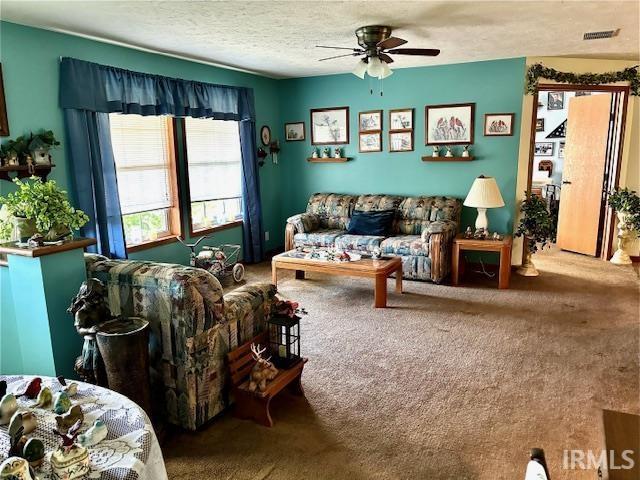 living room with carpet, ceiling fan, and a textured ceiling