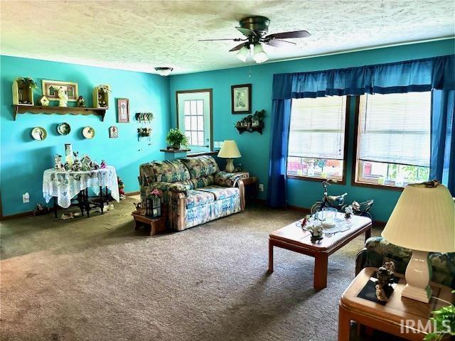 carpeted living room featuring a textured ceiling, ceiling fan, and a healthy amount of sunlight