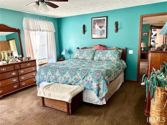 carpeted bedroom featuring ceiling fan and a textured ceiling