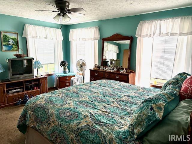 bedroom featuring ceiling fan, carpet flooring, and a textured ceiling