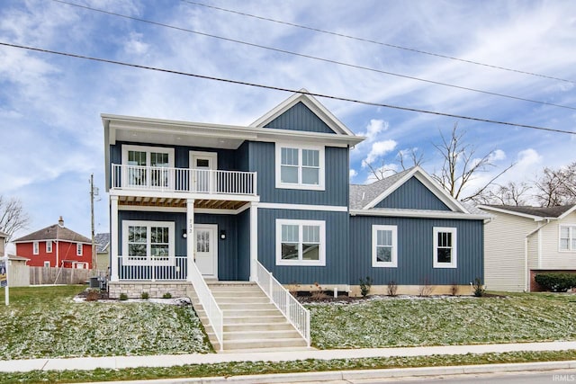 view of front facade with cooling unit, a balcony, covered porch, and a front yard