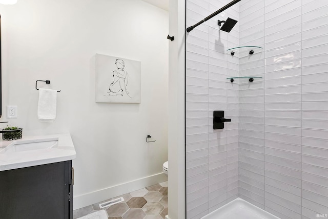 bathroom featuring vanity, toilet, tile patterned flooring, and a tile shower