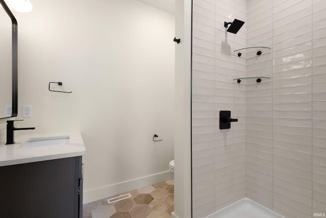 bathroom featuring tiled shower, vanity, toilet, and tile patterned floors