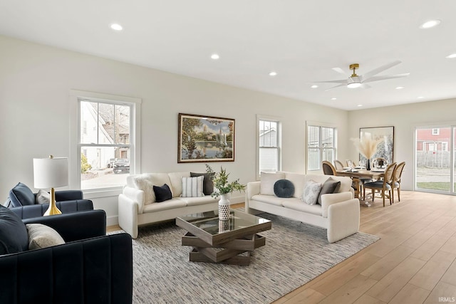 living room with ceiling fan, plenty of natural light, and light wood-type flooring