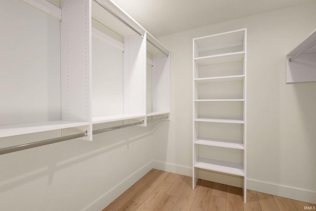 walk in closet with light hardwood / wood-style flooring