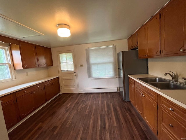 kitchen with dark wood-type flooring, baseboard heating, sink, and stainless steel refrigerator