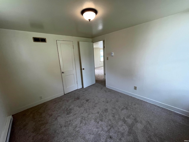 unfurnished bedroom with baseboard heating, a closet, and carpet