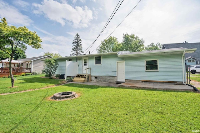 back of property featuring an outdoor fire pit and a yard