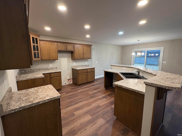 kitchen with an island with sink, an inviting chandelier, dark wood-type flooring, and sink