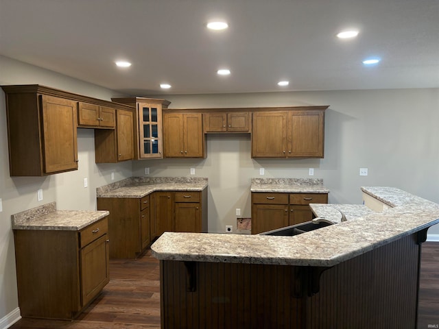 kitchen with a spacious island, a breakfast bar area, dark wood-type flooring, and sink