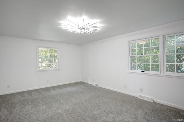 carpeted empty room with a notable chandelier