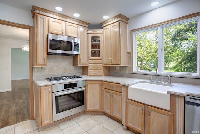 kitchen with decorative backsplash, light brown cabinetry, appliances with stainless steel finishes, light wood-type flooring, and sink