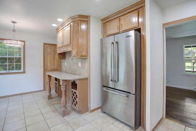 kitchen with light brown cabinets, high quality fridge, pendant lighting, light hardwood / wood-style floors, and tasteful backsplash