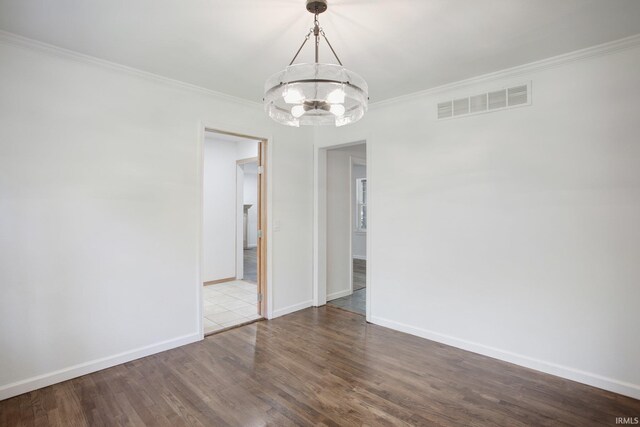 empty room featuring a notable chandelier, ornamental molding, and hardwood / wood-style flooring