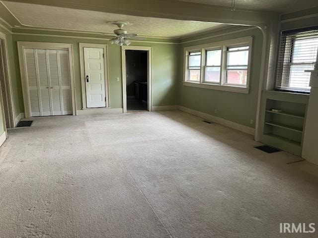 interior space with ceiling fan, light colored carpet, and crown molding