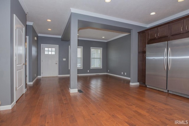 kitchen featuring dark brown cabinets, stainless steel built in refrigerator, dark wood-type flooring, and ornamental molding