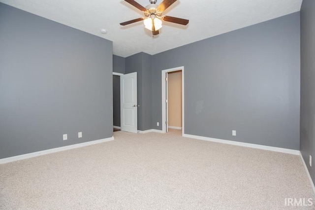 empty room with light colored carpet, baseboards, and a ceiling fan