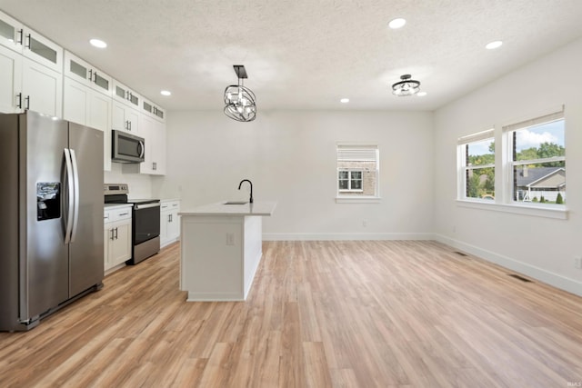 kitchen featuring white cabinetry, sink, an island with sink, pendant lighting, and appliances with stainless steel finishes