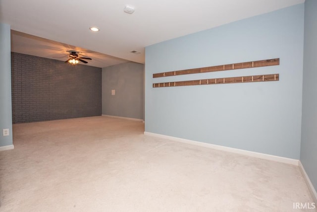 unfurnished room with ceiling fan, light colored carpet, and brick wall