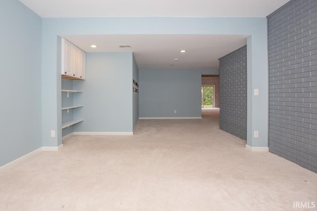 carpeted empty room featuring brick wall