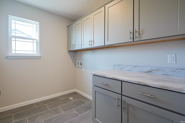 washroom with dark tile patterned flooring, hookup for a washing machine, and cabinets