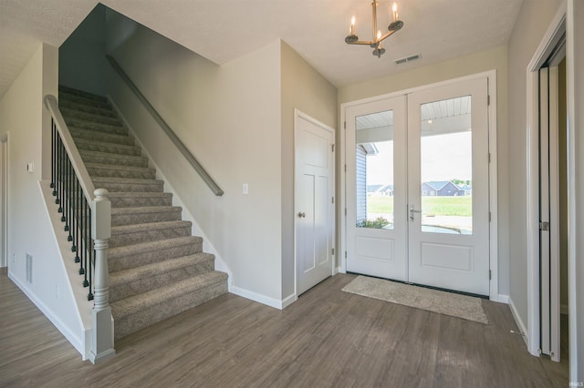 foyer entrance featuring a textured ceiling, an inviting chandelier, hardwood / wood-style flooring, and french doors