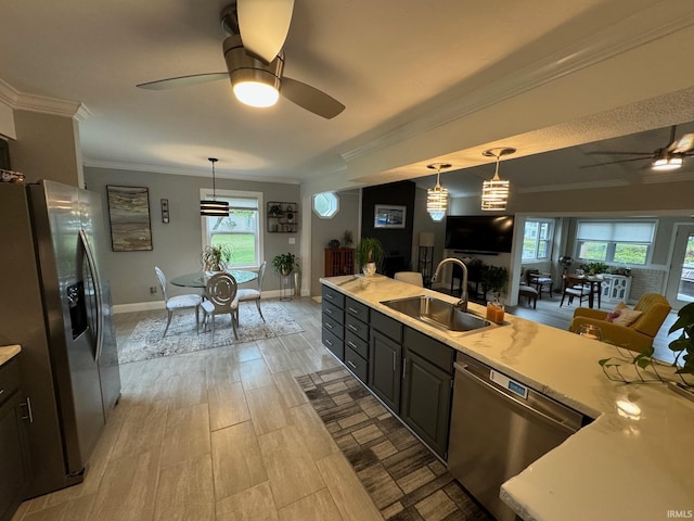 kitchen featuring light countertops, a sink, stainless steel appliances, ceiling fan, and ornamental molding