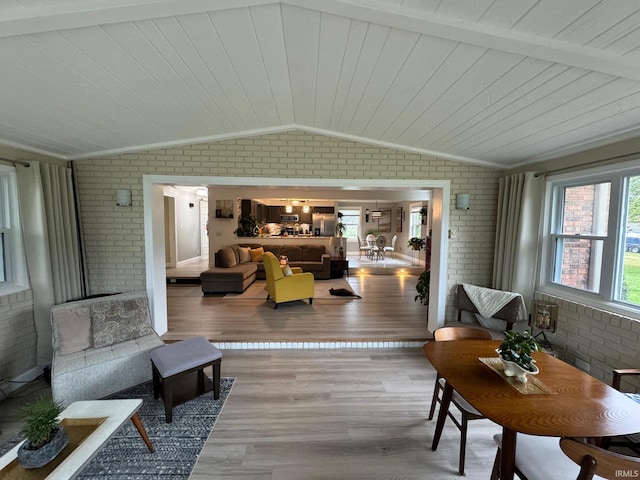 living area featuring crown molding, brick wall, lofted ceiling, and wood finished floors