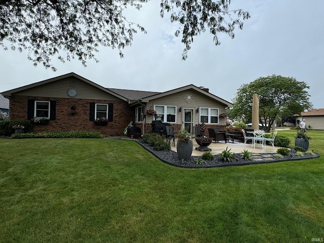 rear view of house featuring brick siding, a yard, and a patio area