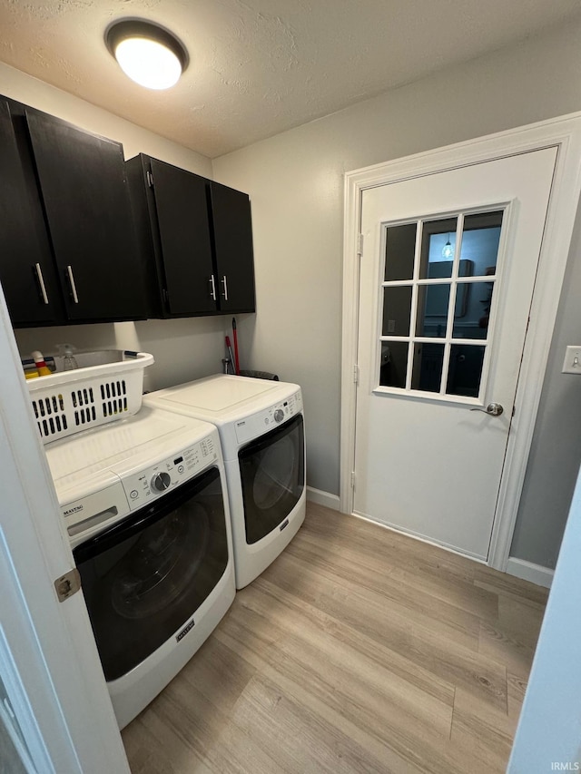 laundry area featuring light wood-type flooring, washing machine and clothes dryer, and cabinets