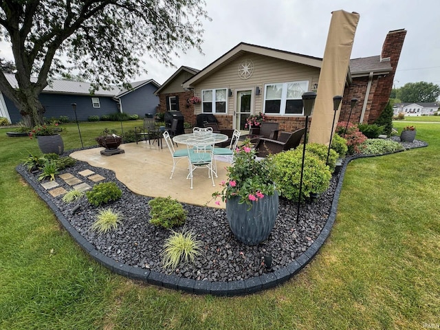 rear view of property featuring a patio, a chimney, brick siding, a lawn, and a fire pit