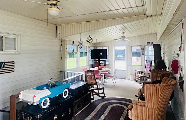 recreation room with ceiling fan, wood walls, and carpet