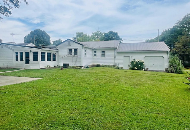 rear view of property with a garage, central AC, metal roof, and a lawn