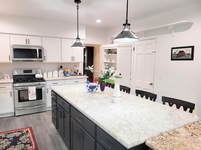 kitchen featuring stainless steel appliances, a kitchen island, hanging light fixtures, and white cabinets