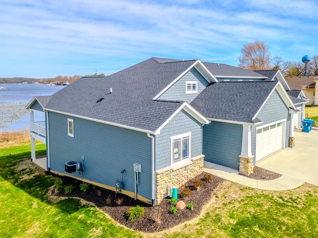 exterior space featuring cooling unit, a garage, a water view, and a yard